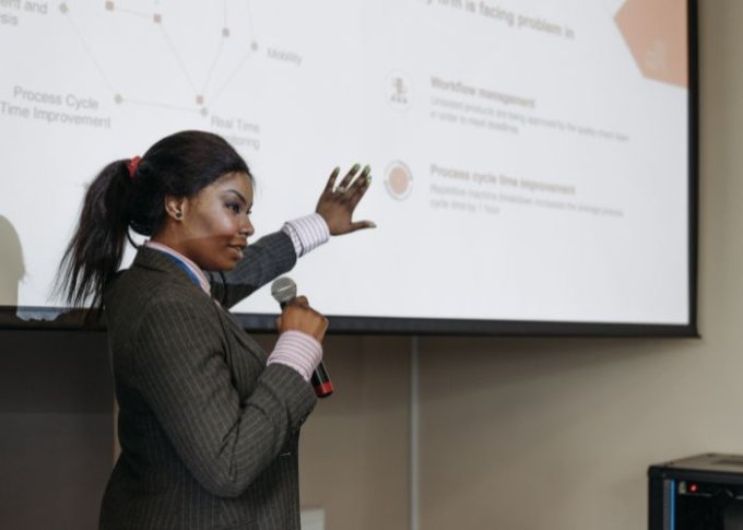 Kobieta używa mikrofonu podłączonego do głośnika Bluetooth podczas prezentacji